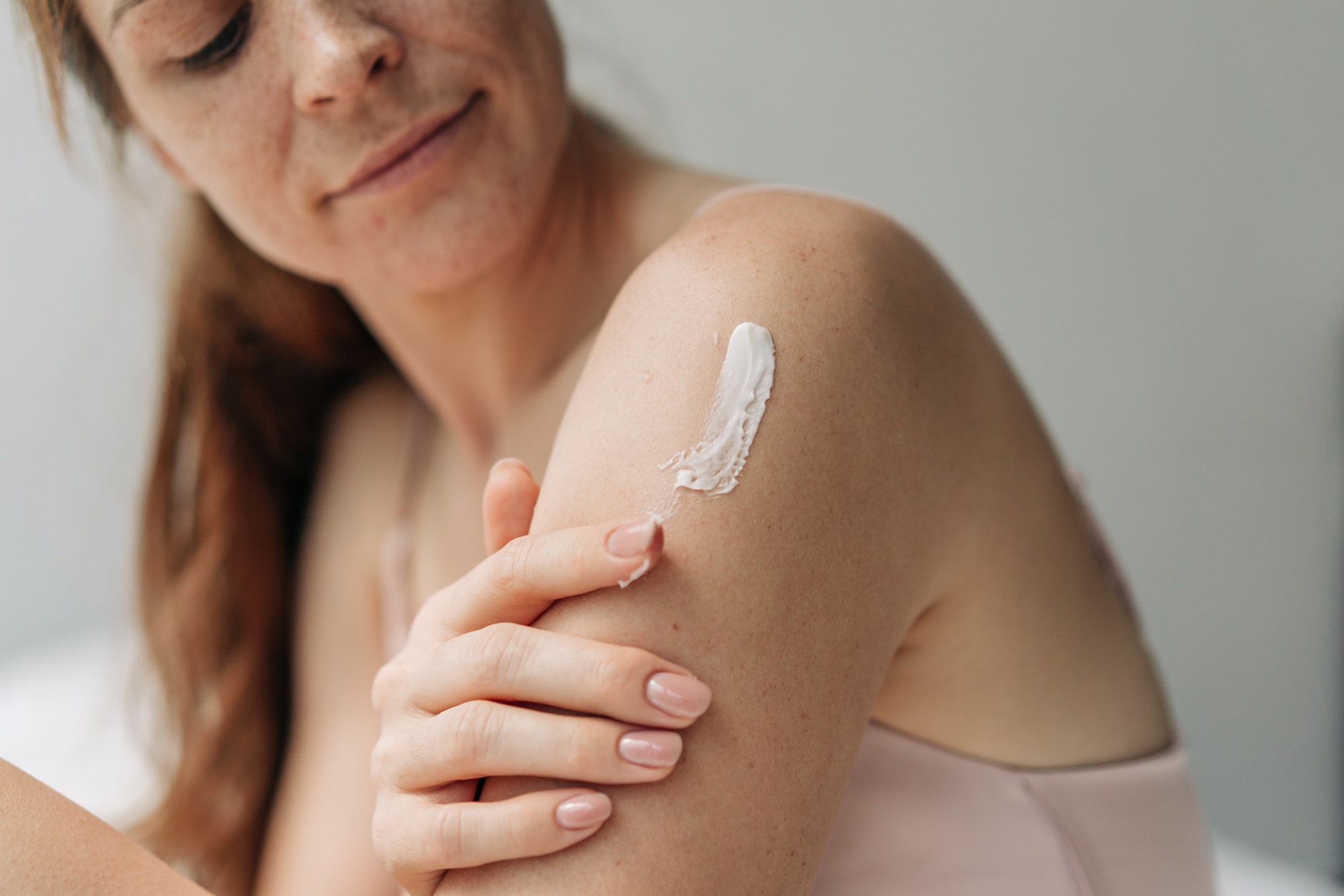Young woman uses body skin care cream. Treat and beauty procedure.