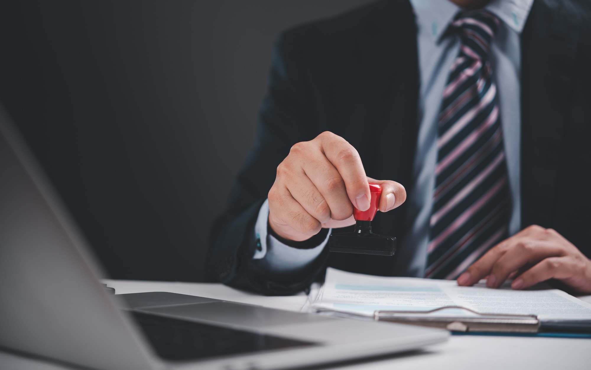Businessman stamping a document for approval, professional process of business documentation.