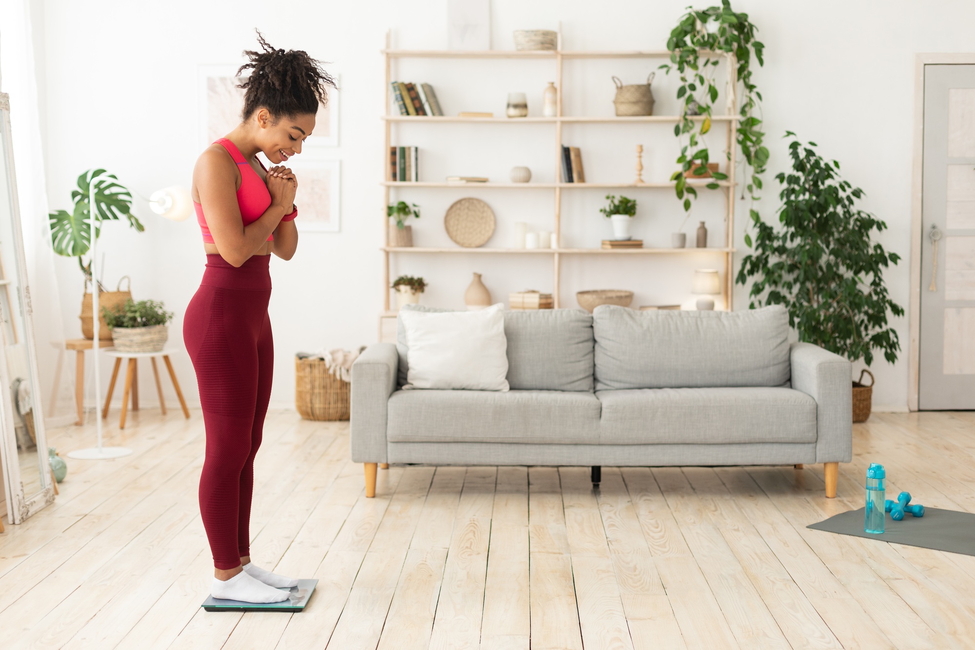 Happy Black Woman Weighing Herself On Weight-Scales Losing Weight Indoor
