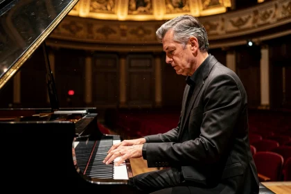 Pianiste français en costume noir jouant sur un piano à queue dans une grande salle de concert classique